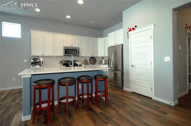 kitchen with white cabinetry, sink, stainless steel appliances, dark hardwood / wood-style floors, and a breakfast bar area