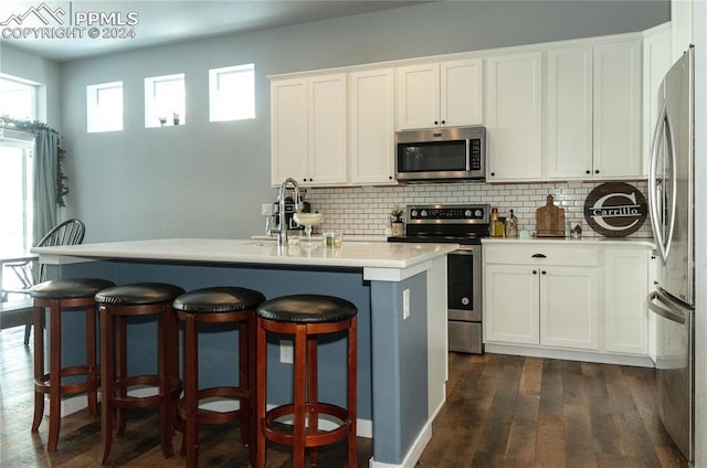 kitchen with a center island with sink, white cabinetry, sink, and appliances with stainless steel finishes