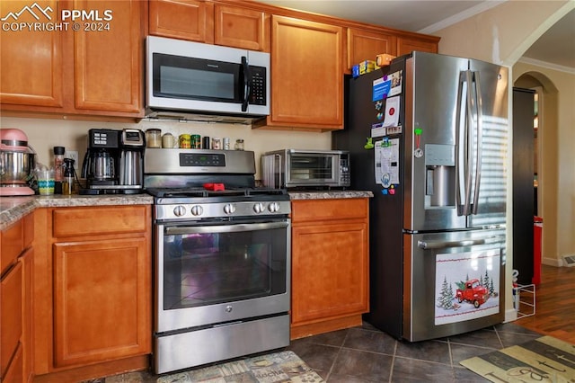 kitchen with crown molding, dark tile patterned flooring, and appliances with stainless steel finishes