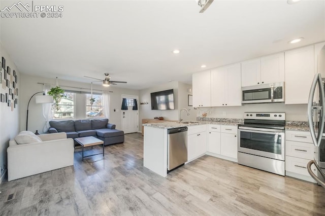 kitchen with white cabinets, sink, appliances with stainless steel finishes, light hardwood / wood-style floors, and kitchen peninsula