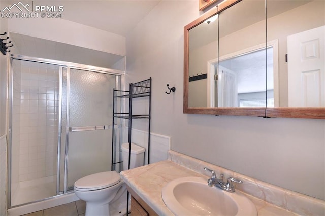 bathroom with tile patterned flooring, vanity, toilet, and walk in shower