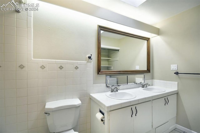 bathroom featuring vanity, toilet, and tile walls