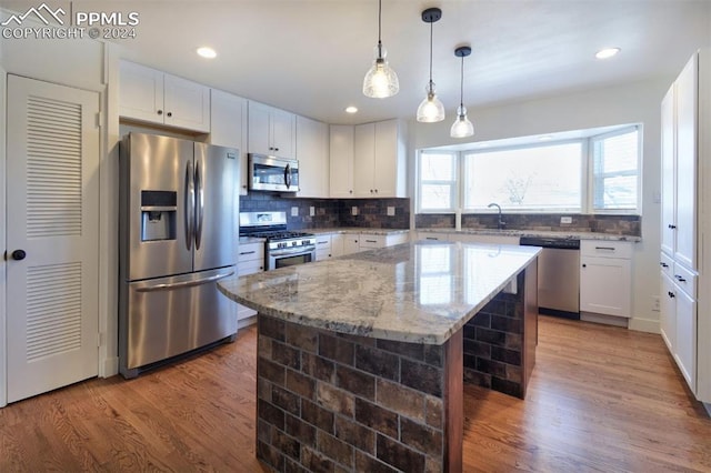 kitchen featuring light stone countertops, white cabinetry, dark wood-type flooring, stainless steel appliances, and a kitchen island