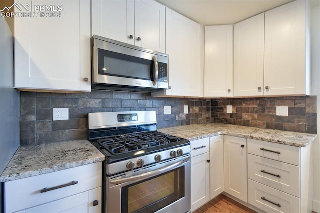 kitchen with backsplash, light wood-type flooring, white cabinetry, and stainless steel appliances