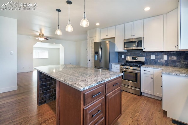 kitchen with white cabinets, a center island, stainless steel appliances, and dark wood-type flooring