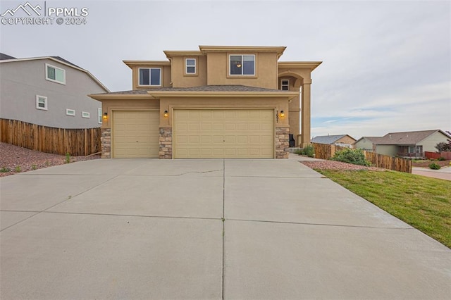 view of front of property with stone siding, fence, concrete driveway, and stucco siding