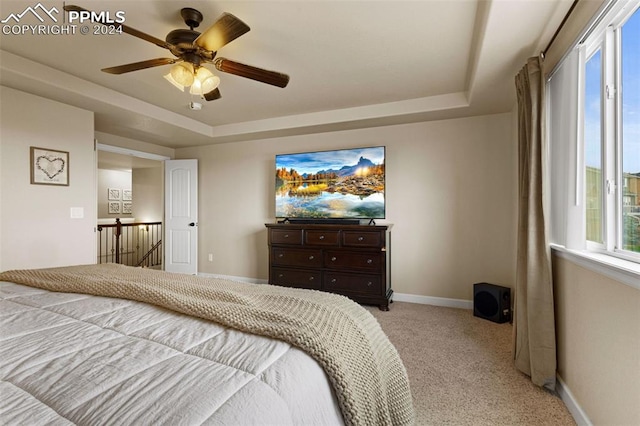 bedroom with baseboards, a raised ceiling, a ceiling fan, and light colored carpet