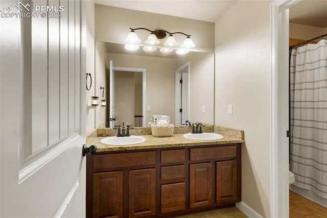 full bath featuring tile patterned flooring, a sink, toilet, and double vanity