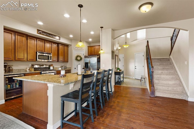 kitchen with pendant lighting, a center island with sink, stainless steel appliances, and dark hardwood / wood-style floors