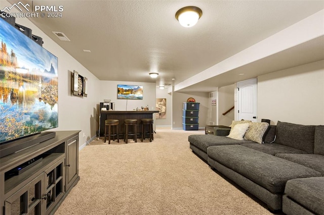 living area with a dry bar, visible vents, light carpet, a textured ceiling, and baseboards