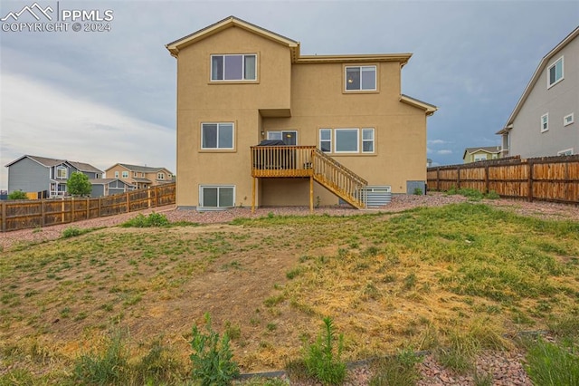 rear view of property featuring a fenced backyard, a yard, stairway, and stucco siding