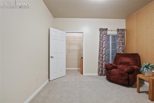 living area featuring wooden walls and light colored carpet