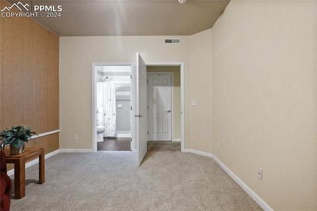 bedroom with ensuite bathroom and light colored carpet