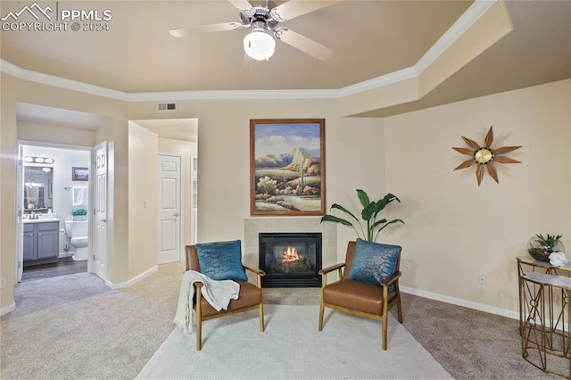 sitting room with a tile fireplace, ceiling fan, light colored carpet, and ornamental molding