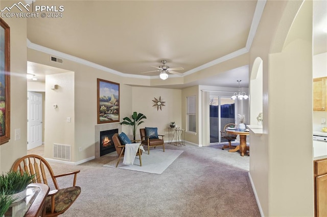 living area with ceiling fan with notable chandelier, ornamental molding, and light carpet