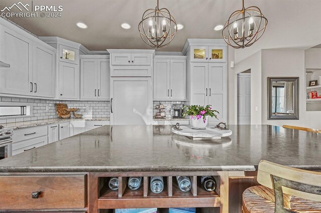 kitchen with white cabinetry, decorative light fixtures, light stone countertops, and a chandelier