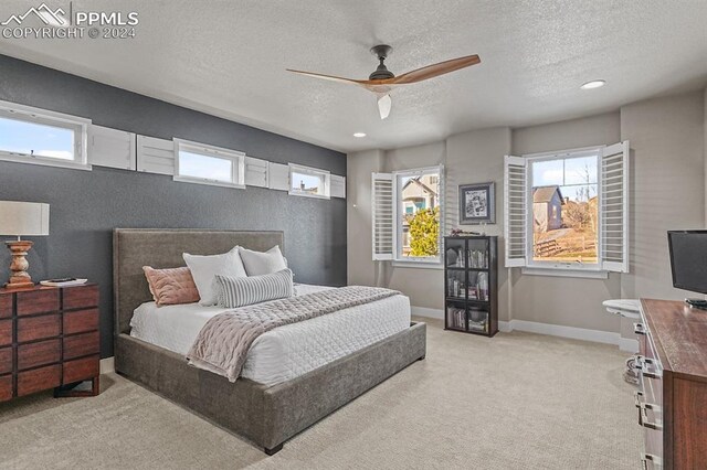 carpeted bedroom with ceiling fan and a textured ceiling