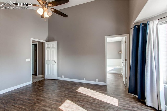 unfurnished room with ceiling fan, dark hardwood / wood-style flooring, and a towering ceiling