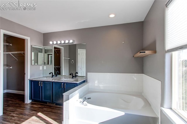 bathroom with vanity, a healthy amount of sunlight, wood-type flooring, and a bath