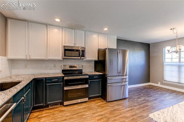 kitchen featuring a notable chandelier, white cabinets, decorative light fixtures, and appliances with stainless steel finishes