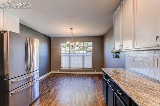 kitchen with white cabinets, pendant lighting, light stone countertops, and stainless steel refrigerator