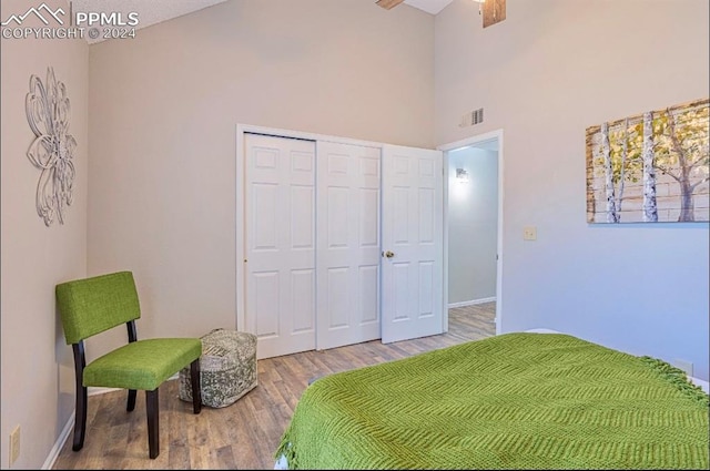 bedroom with wood-type flooring, a towering ceiling, a closet, and ceiling fan