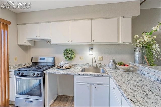 kitchen with gas range, sink, light stone counters, light hardwood / wood-style flooring, and white cabinets