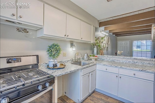 kitchen featuring stainless steel gas stove, white cabinetry, sink, and light hardwood / wood-style flooring