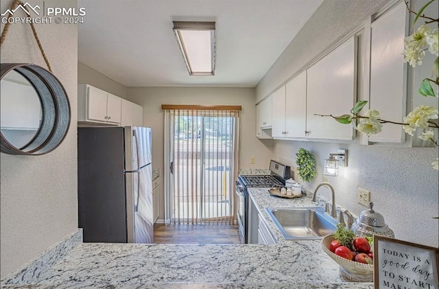 kitchen with light stone countertops, white cabinetry, sink, stainless steel appliances, and dark hardwood / wood-style flooring