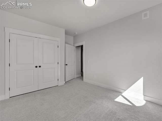 unfurnished bedroom featuring light colored carpet and a closet