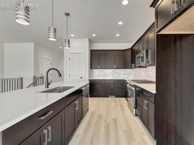 kitchen featuring sink, light hardwood / wood-style flooring, decorative light fixtures, dark brown cabinets, and stainless steel appliances