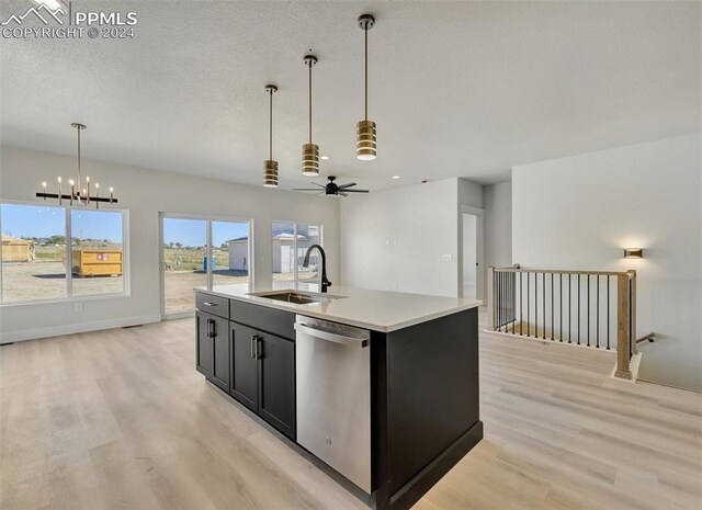 kitchen with light wood-type flooring, ceiling fan with notable chandelier, a kitchen island with sink, sink, and dishwasher