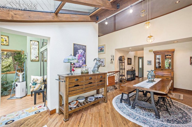 dining room with beam ceiling, light wood-type flooring, track lighting, and a healthy amount of sunlight