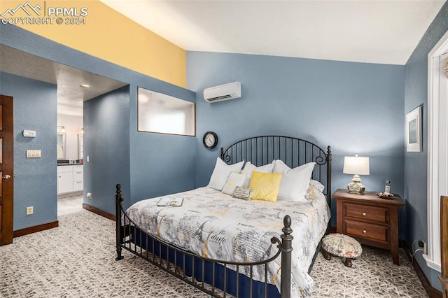 bedroom with ensuite bathroom, an AC wall unit, and carpet floors