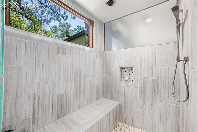 bathroom with tiled shower and plenty of natural light