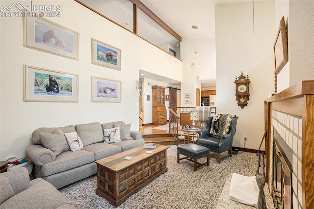 living room with a tile fireplace and a towering ceiling