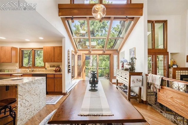 dining space featuring sink, light hardwood / wood-style flooring, a tile fireplace, and a baseboard radiator