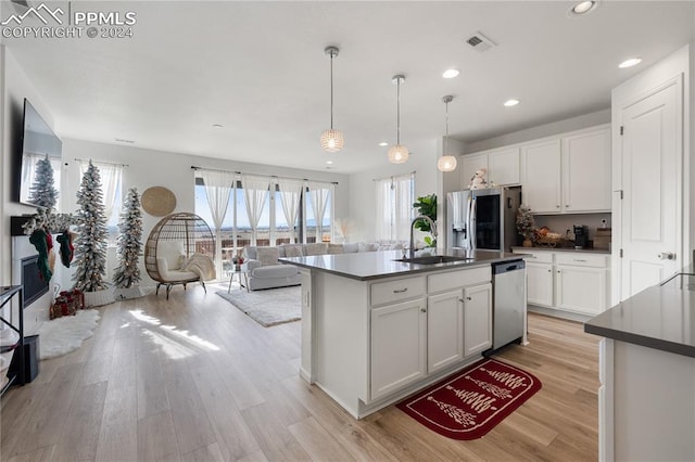 kitchen with white cabinets, hanging light fixtures, sink, an island with sink, and appliances with stainless steel finishes