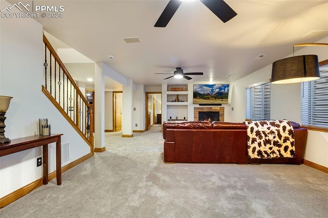 living room featuring ceiling fan, a stone fireplace, and light colored carpet