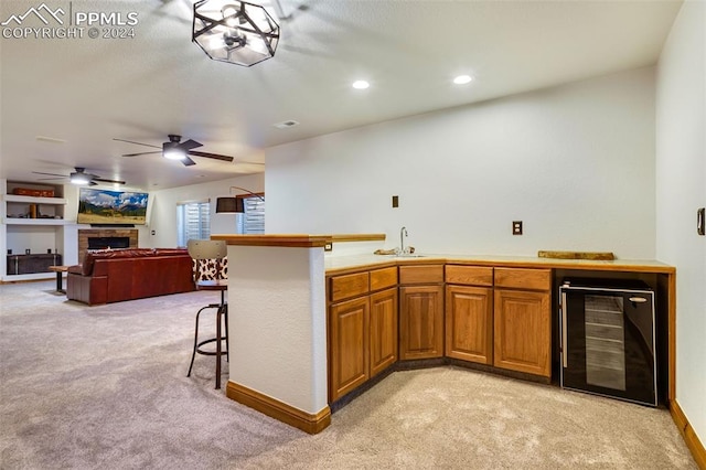 kitchen with a breakfast bar area, light carpet, sink, and beverage cooler