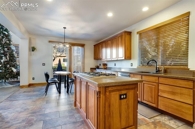 kitchen with stainless steel appliances, sink, decorative light fixtures, a notable chandelier, and a center island