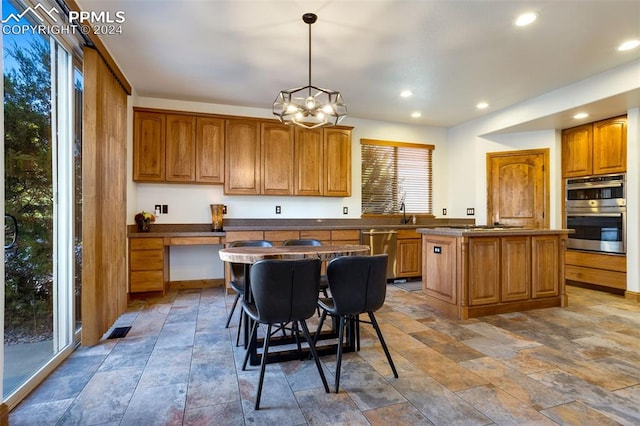 kitchen featuring stainless steel appliances, pendant lighting, an inviting chandelier, a center island, and a breakfast bar area