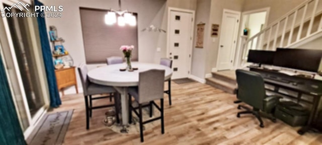 dining space with light hardwood / wood-style flooring and a notable chandelier