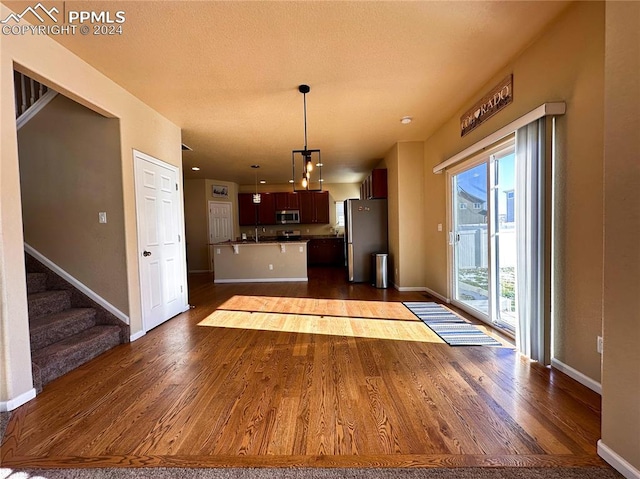 kitchen featuring baseboards, appliances with stainless steel finishes, open floor plan, and dark wood finished floors