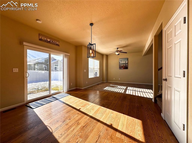 interior space with ceiling fan with notable chandelier, a textured ceiling, and dark hardwood / wood-style flooring