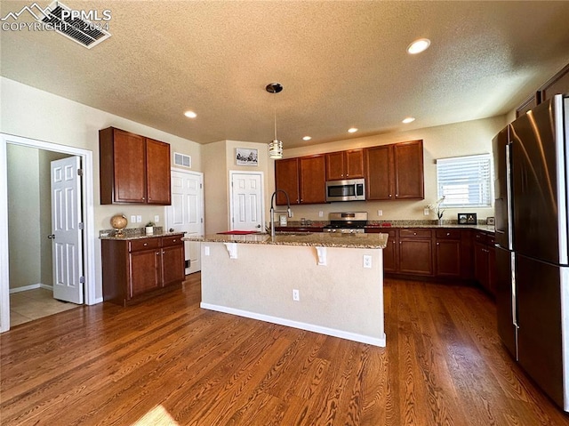 kitchen with stainless steel appliances, visible vents, a sink, and dark wood-style floors