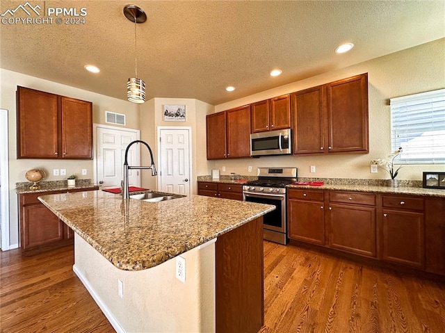 kitchen with stainless steel appliances, wood finished floors, a sink, and visible vents