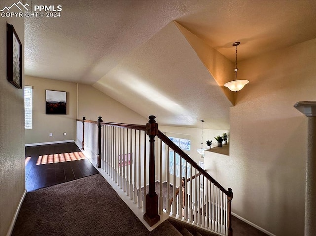 corridor featuring a textured ceiling, lofted ceiling, carpet floors, an upstairs landing, and baseboards