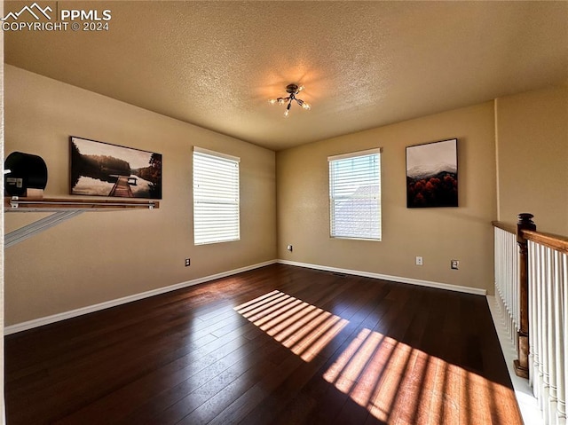 spare room featuring dark hardwood / wood-style flooring and a textured ceiling