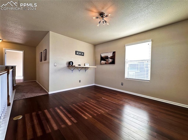 empty room featuring a textured ceiling and dark wood-type flooring